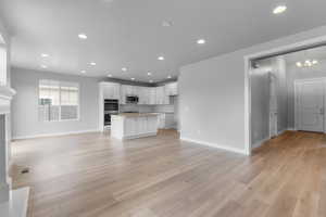 Unfurnished living room with an inviting chandelier and light hardwood / wood-style floors