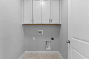 Washroom with hookup for a washing machine, cabinets, and electric dryer hookup