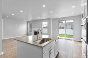 Kitchen featuring dishwasher, white cabinetry, a center island with sink, and sink