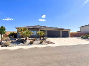 View of front of property featuring an attached garage, a tile roof, stucco siding, and concrete driveway