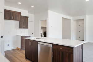 Kitchen featuring sink, light hardwood / wood-style floors, an island with sink, and stainless steel dishwasher