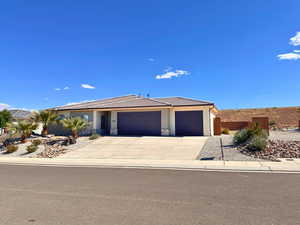 View of front facade featuring a garage, stucco siding, driveway, and a tile roof