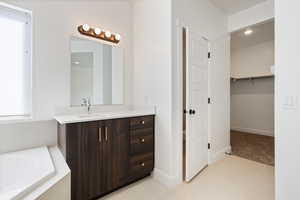 Bathroom with tile patterned flooring, vanity, and a bath