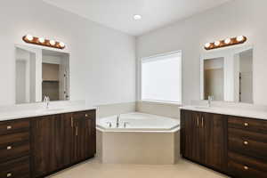 Bathroom featuring tile patterned floors, tiled bath, and vanity