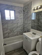 Full bathroom featuring vanity, toilet, tiled shower / bath combo, and a textured ceiling