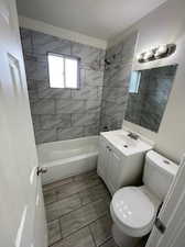 Full bathroom with toilet, tiled shower / bath combo, and vanity