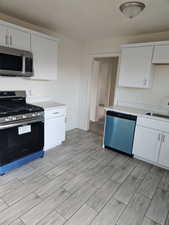 Kitchen featuring sink, appliances with stainless steel finishes, white cabinets, and light hardwood / wood-style floors