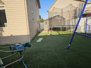 View of yard featuring a trampoline and a playground