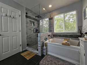 Bathroom featuring a textured ceiling, shower with separate bathtub, tile patterned flooring, and tile walls