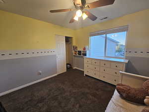 Unfurnished bedroom featuring dark carpet, a closet, and ceiling fan