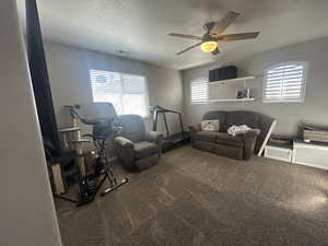 Living room with ceiling fan, a textured ceiling, and carpet flooring