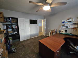 Office space featuring a textured ceiling, ceiling fan, and dark colored carpet