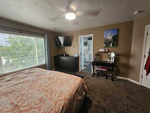 Carpeted bedroom with ceiling fan and a textured ceiling