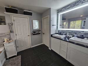 Bathroom featuring a textured ceiling, vanity, a bath, and backsplash