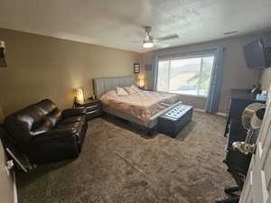 Carpeted bedroom featuring a textured ceiling and ceiling fan