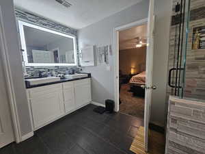 Bathroom featuring a textured ceiling, vanity, walk in shower, decorative backsplash, and ceiling fan