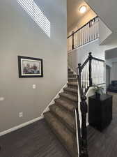 Staircase featuring hardwood / wood-style floors and a towering ceiling