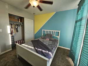 Carpeted bedroom with ceiling fan and a closet