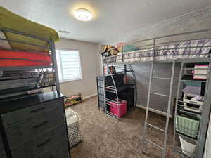 Carpeted bedroom with a textured ceiling