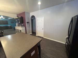 Kitchen with ceiling fan, black fridge, and dark hardwood / wood-style floors