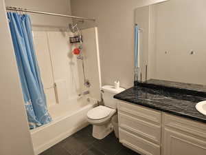 Full bathroom with vanity, toilet, tile patterned floors, and shower / bathtub combination with curtain