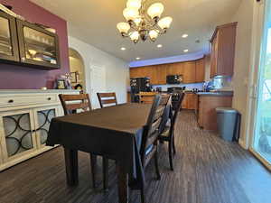 Dining room with dark wood-type flooring and an inviting chandelier