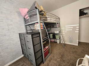 Bedroom featuring dark colored carpet and a textured ceiling