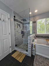 Bathroom with independent shower and bath, a textured ceiling, and tile patterned flooring