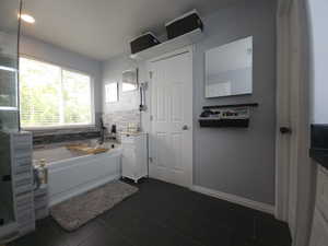 Bathroom featuring tile patterned flooring, a bath, vanity, and backsplash