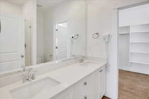 Primary ensuite bathroom with double sinks and walk-in closet