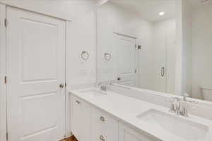 Primary ensuite bathroom with double sinks and large shower with glass doors