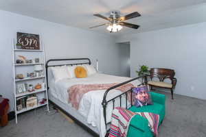 Bedroom with carpet floors, ceiling fan, and a textured ceiling