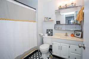 Bathroom with tile patterned floors, curtained shower, vanity, and toilet