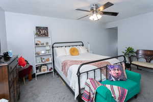 Carpeted bedroom featuring ceiling fan and a textured ceiling