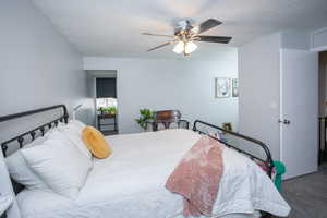 Carpeted bedroom featuring ceiling fan and a textured ceiling