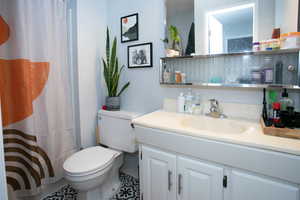 Bathroom with toilet, walk in shower, tile patterned flooring, and vanity