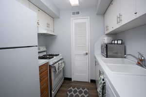 Kitchen featuring white cabinetry, sink, dark hardwood / wood-style flooring, and white appliances