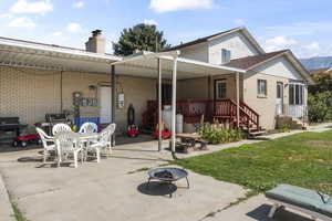 Rear view of house featuring a patio area, a mountain view, a yard, and an outdoor fire pit