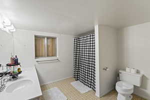 Bathroom with curtained shower, toilet, and vanity