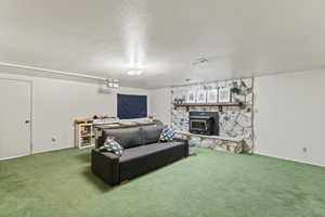 Living room featuring a fireplace, carpet, and a textured ceiling