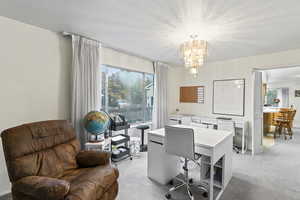 Office space featuring an inviting chandelier and light colored carpet