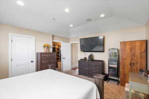 Bedroom with a closet, light colored carpet, a spacious closet, and vaulted ceiling