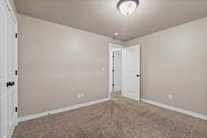 Carpeted empty room featuring a textured ceiling