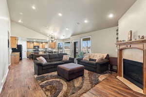 Living room with hardwood / wood-style floors, high vaulted ceiling, a fireplace, and an inviting chandelier