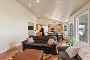 Living room featuring high vaulted ceiling, an inviting chandelier, and light hardwood / wood-style floors