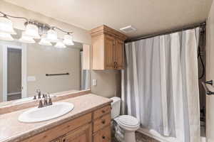 Bathroom featuring vanity, toilet, a shower with curtain, and a textured ceiling