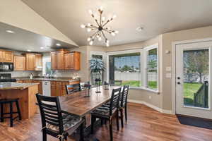 Dining room with lofted ceiling, dark hardwood / wood-style flooring, sink, and a chandelier