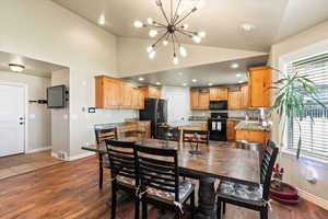 Dining room featuring dark wood-type flooring, high vaulted ceiling, an inviting chandelier, and sink