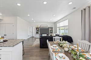 Kitchen featuring dark wood-type flooring, white cabinets, light stone countertops, and a breakfast bar