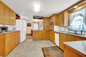 Kitchen with white appliances, kitchen peninsula, sink, and decorative backsplash